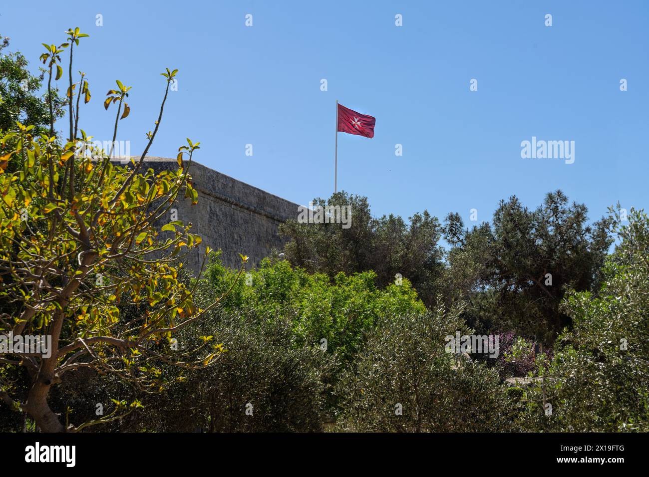 Valletta, Malte, 3 avril 2024. Le drapeau avec la croix maltaise volant sur les remparts dans le centre-ville Banque D'Images