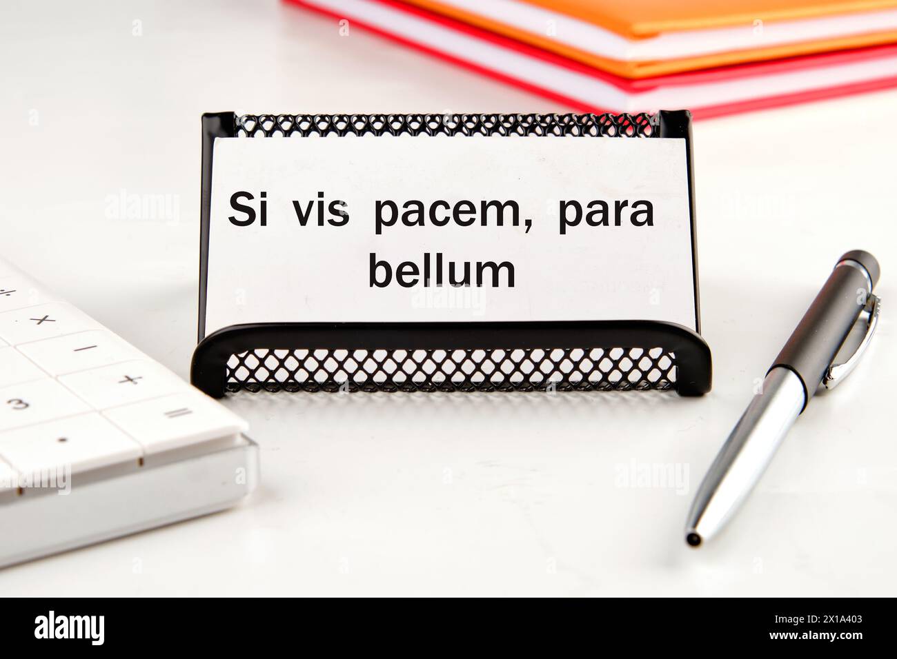 Si vis pacem, para bellum. Phrase latine signifiant si vous voulez la paix, préparez-vous à la guerre. sur une carte de visite blanche à côté d'une calculatrice, d'un bloc-notes et d'un stylo Banque D'Images