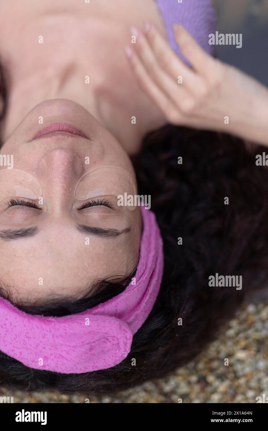 Une femme avec des patchs oculaires couchés dans le bain de spa avec ses yeux fermés dans la relaxation. Banque D'Images