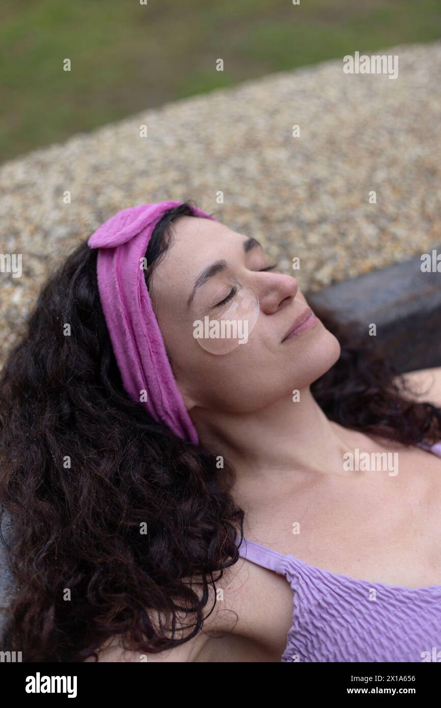 Une femme dans un top violet avec des patchs oculaires dans le spa Banque D'Images