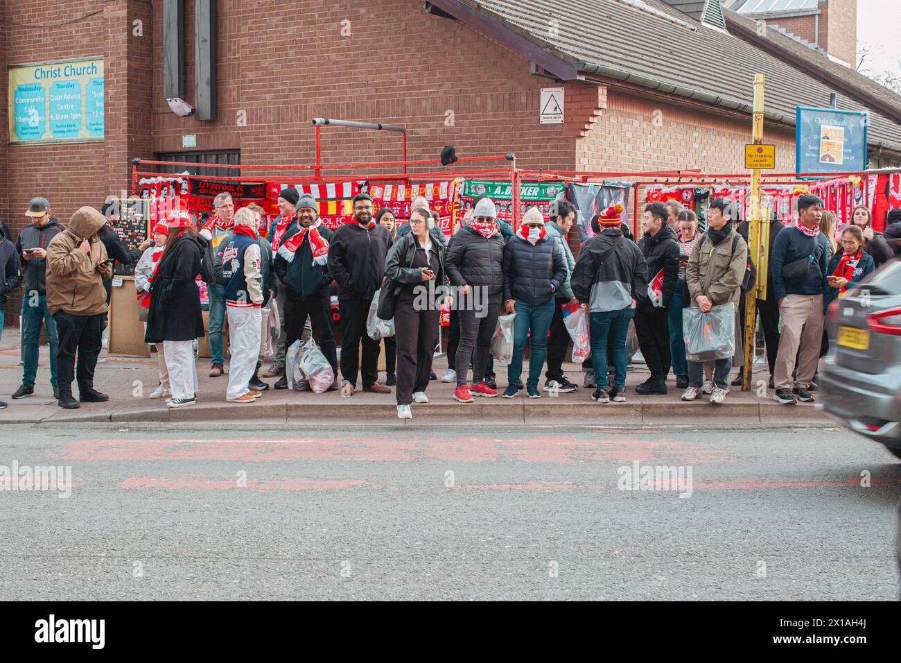 Les fans de football de Liverpool attendent à l'arrêt de bus sur Anfield Road après le match. Banque D'Images