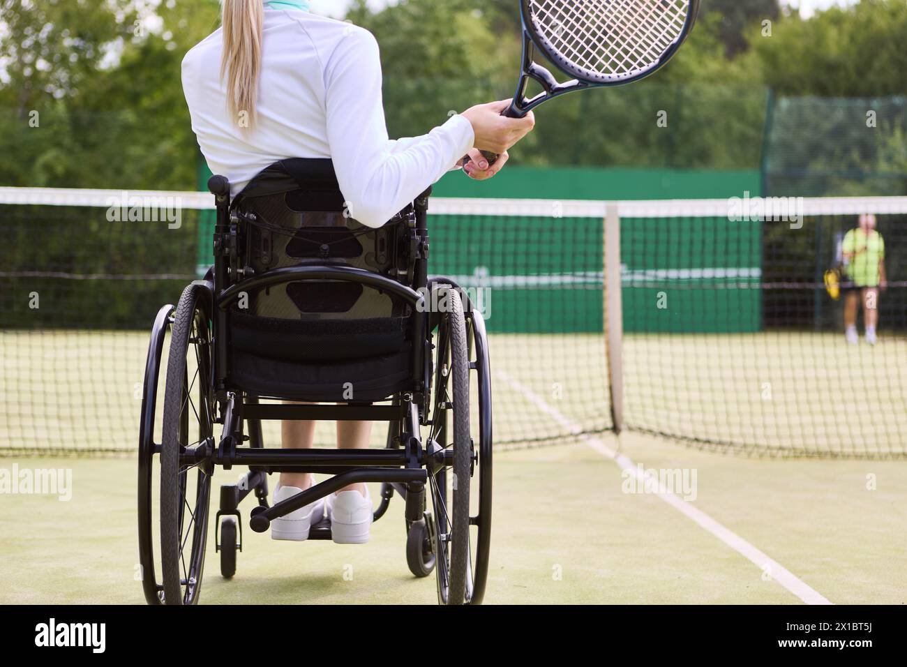 Une image inspirante d'une athlète handicapée jouant au tennis sur un court extérieur, faisant preuve de détermination et d'habileté. Banque D'Images