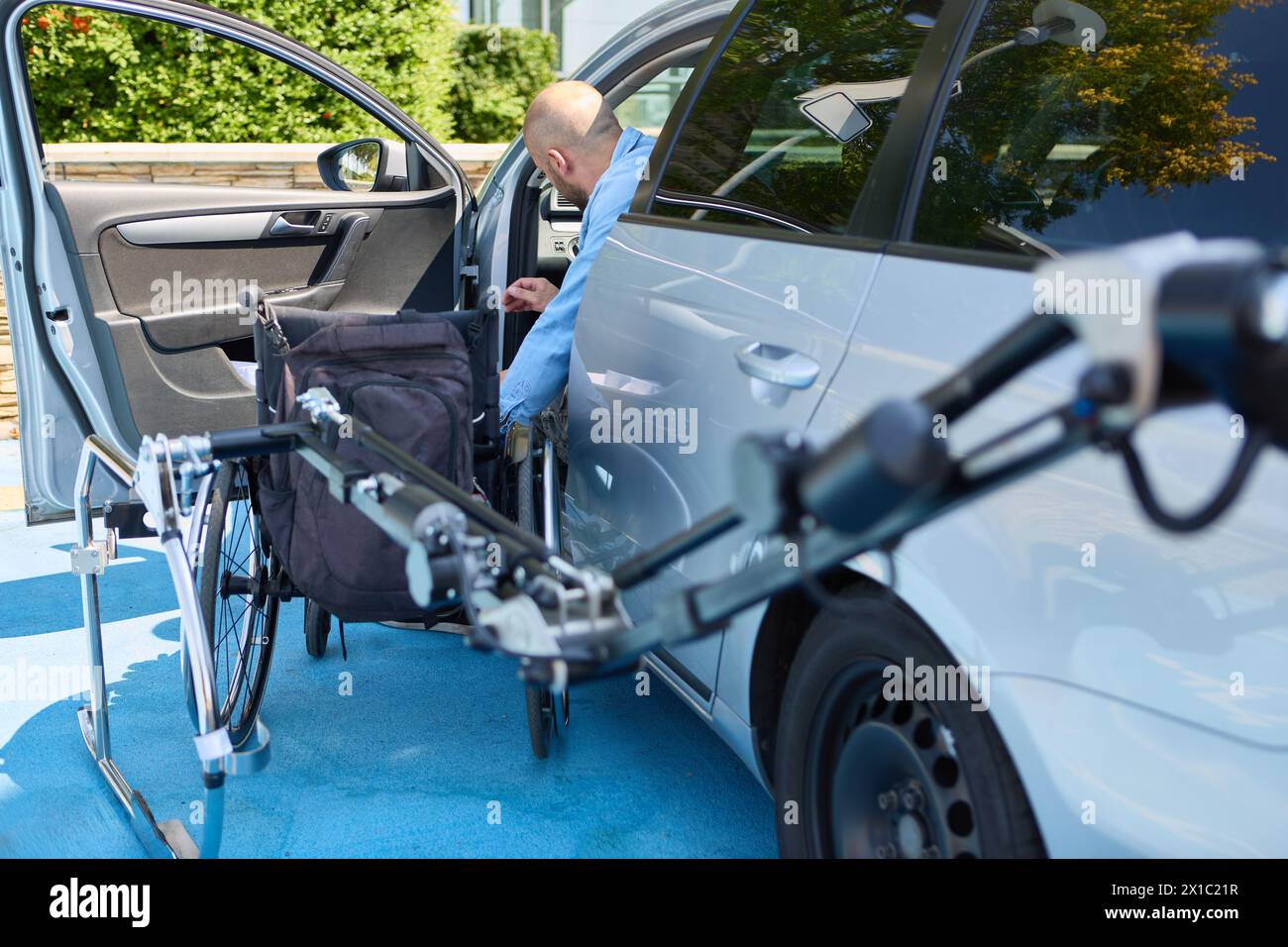 Un homme utilisant un fauteuil roulant alors qu’il se déplace dans une voiture, représentant la mobilité et l’indépendance des personnes handicapées. Banque D'Images