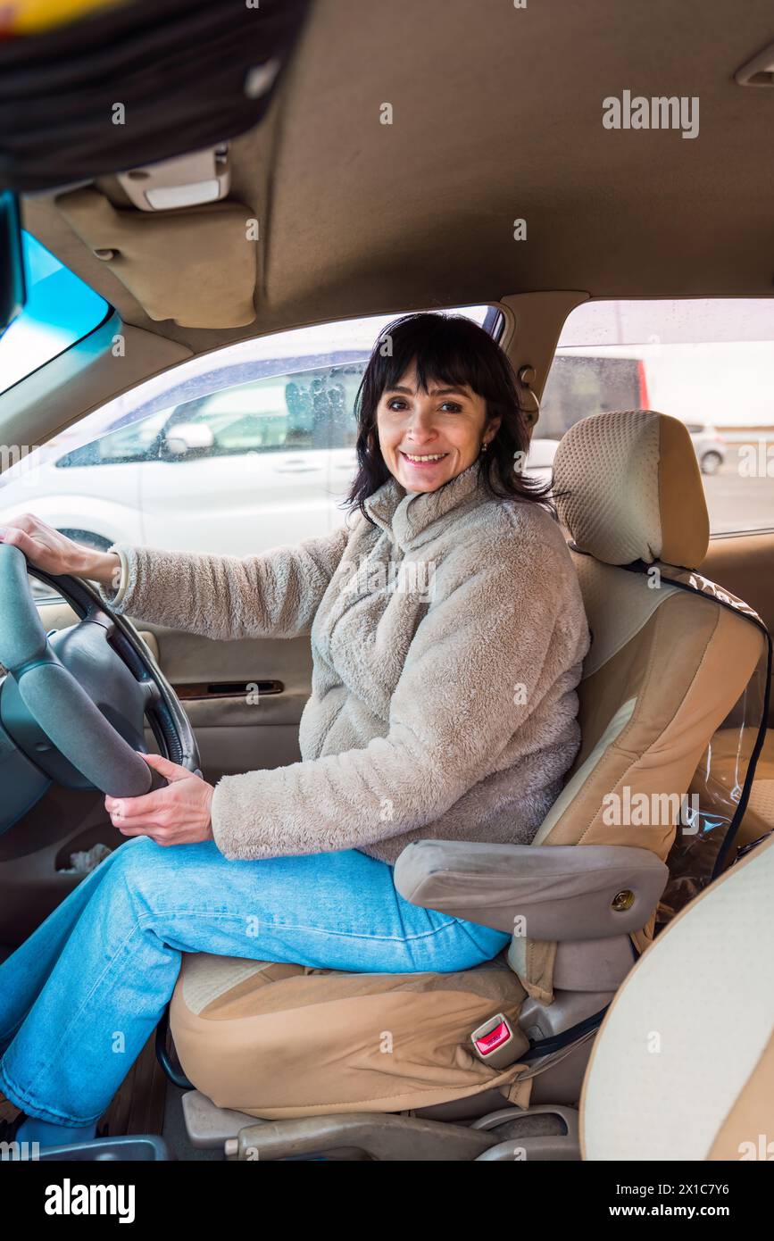 Jeune femme attrayante de 49 ans en veste conduisant la voiture Banque D'Images