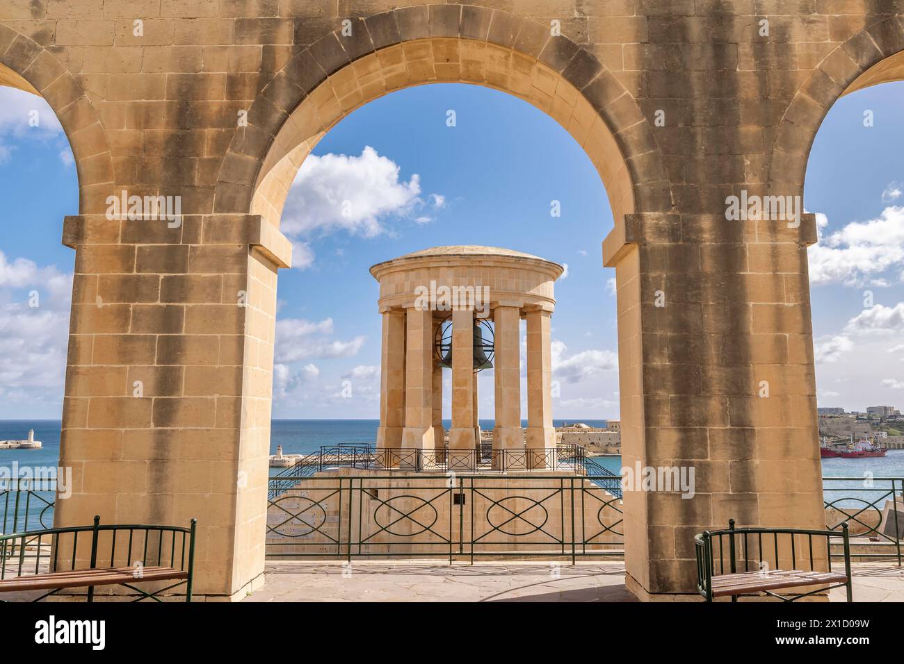 Le Mémorial de guerre de la cloche de siège encadré par une arche des jardins inférieurs de Barrakka, la Valette, Malte Banque D'Images