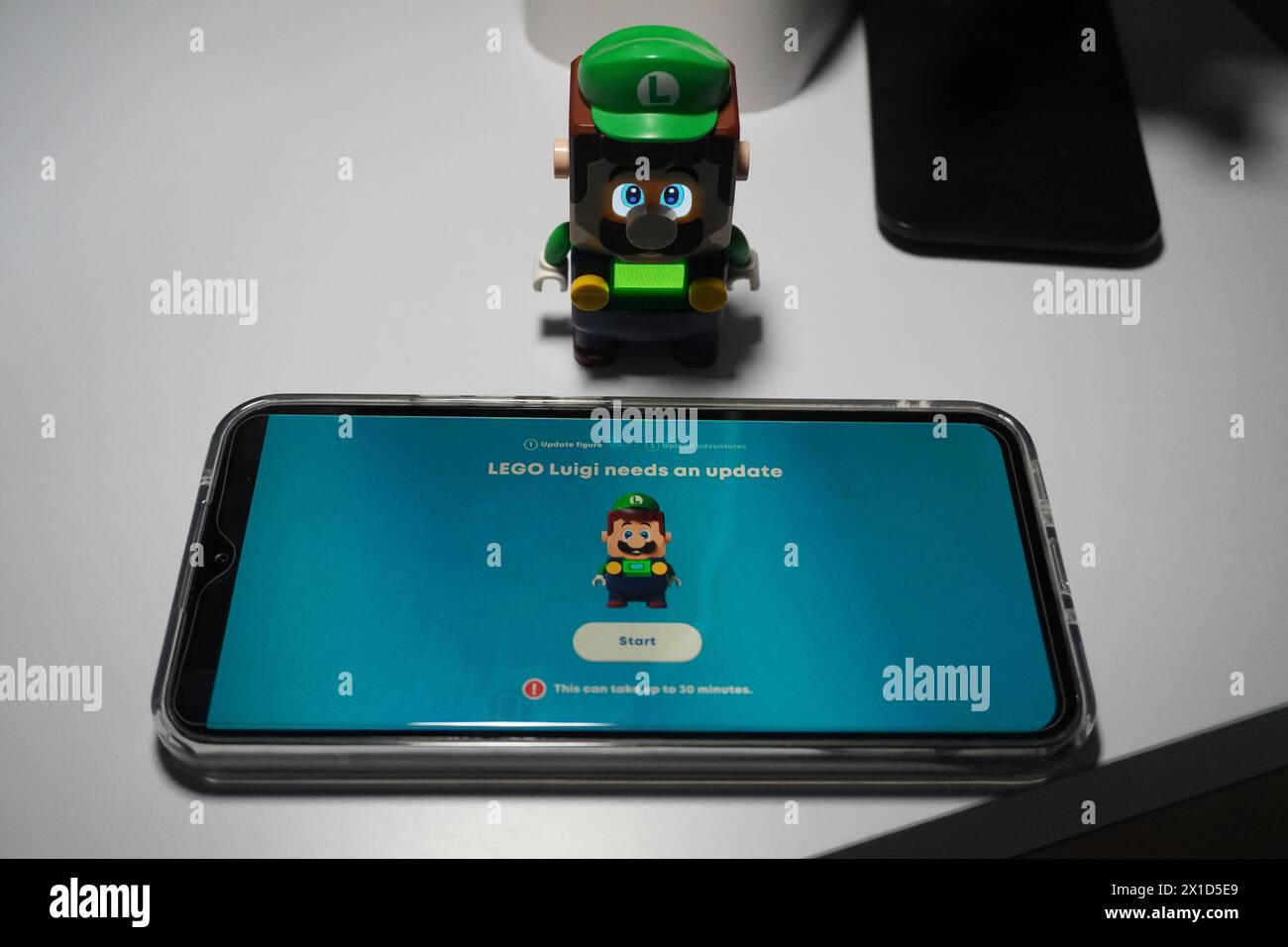 Une figure de Luigi du dessin animé Super Mario Bros qui s'allume et est placée près d'un téléphone portable allumé Banque D'Images