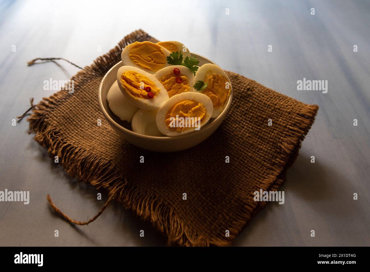 Oeufs durs tranchés dans un bol avec des feuilles de persil. Banque D'Images