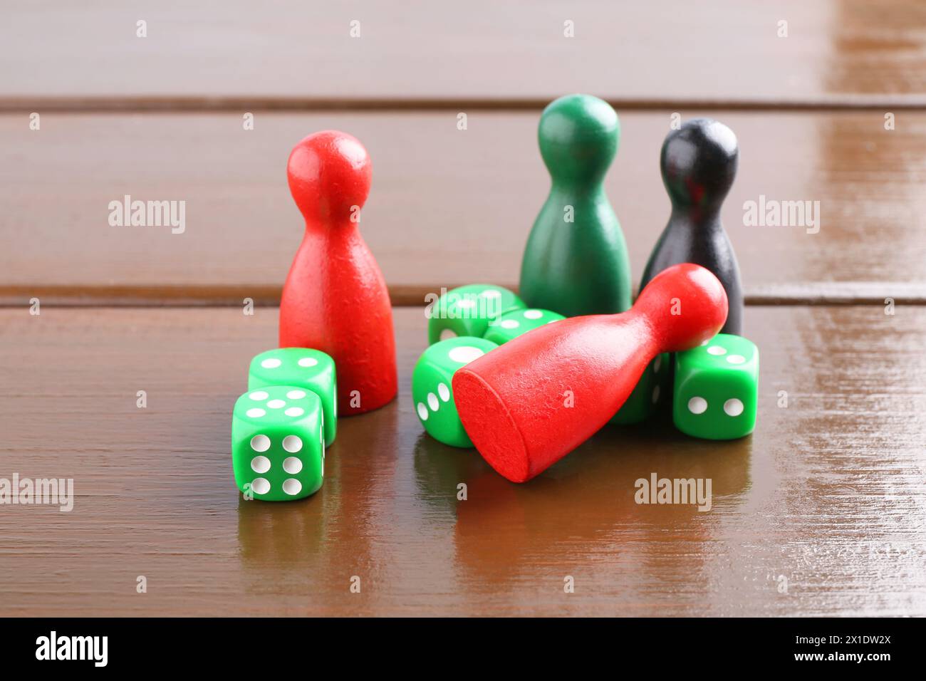 Dés verts et pièces de jeu de couleur sur la table en bois, gros plan Banque D'Images