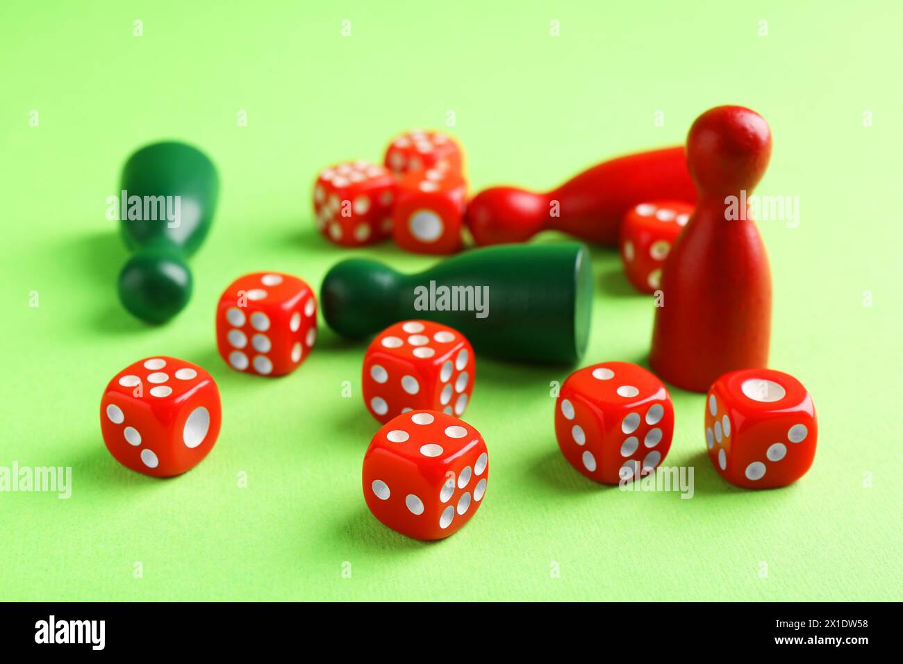 Beaucoup de dés rouges et de pièces de jeu de couleur sur fond vert Banque D'Images