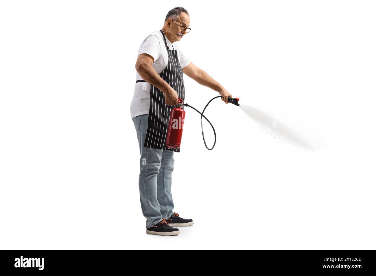 Homme mûr avec un tablier de cuisine utilisant un extincteur isolé sur fond blanc Banque D'Images