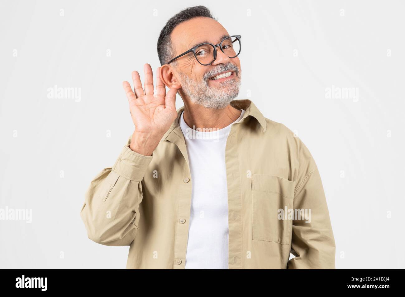 Homme âgé tenant la main derrière l'oreille demandant à parler plus fort Banque D'Images