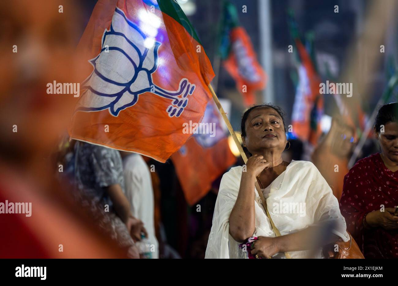 Des partisans du Bharatiya Janata Party (BJP) tenant le drapeau du BJP en attente de la tournée de Narendra Modi, lors d'une campagne électorale à Guwahati, Assam, Inde, le 16 avril 2024. Crédit : David Talukdar/Alamy Live News Banque D'Images