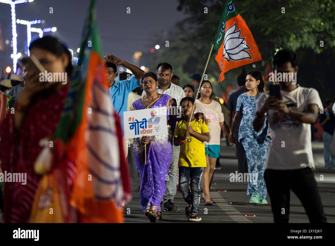 Des partisans du Bharatiya Janata Party (BJP) tenant le drapeau du BJP en attente de la tournée de Narendra Modi, lors d'une campagne électorale à Guwahati, Assam, Inde, le 16 avril 2024. Crédit : David Talukdar/Alamy Live News Banque D'Images