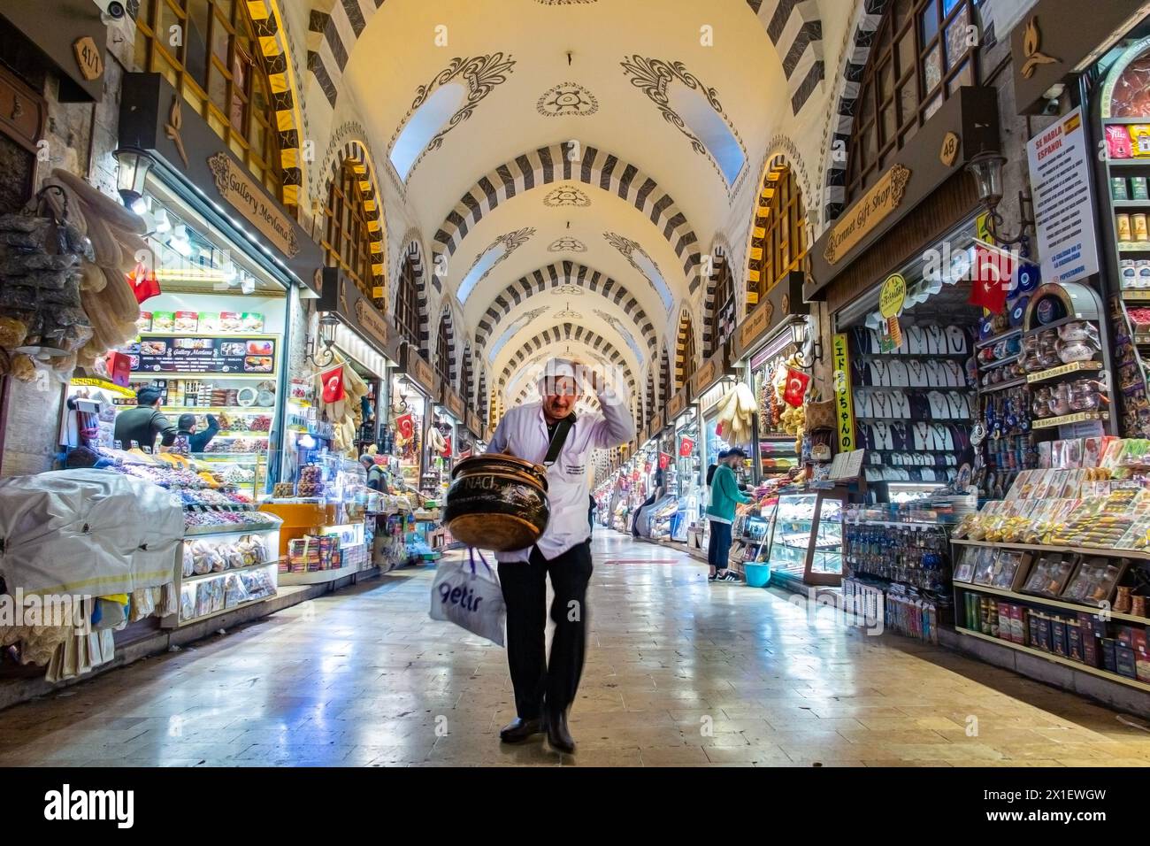 Un sympathique vendeur de thé escamote son chapeau à l'intérieur du marché couvert égyptien, célèbre pour ses épices à Istanbul, en Turquie Banque D'Images