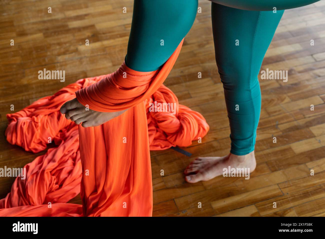 Jeune femme latino-américaine (33 ans) en classe avec des tissus de gymnastique aérienne apprend la technique de la fixation du pied pour grimper en toute sécurité. Yoga et bien-être Concepp Banque D'Images