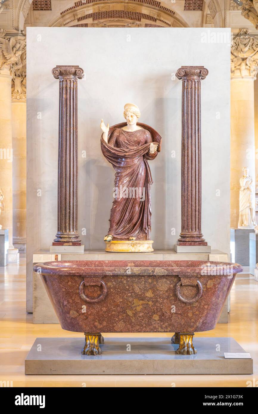 Femme en prière entre deux colonnes ioniques. Une femme dans une robe drapée se tient debout priant entre deux colonnes ioniques à l'intérieur du musée du Louvre, exposant l'antiquité classique. Paris, France Banque D'Images