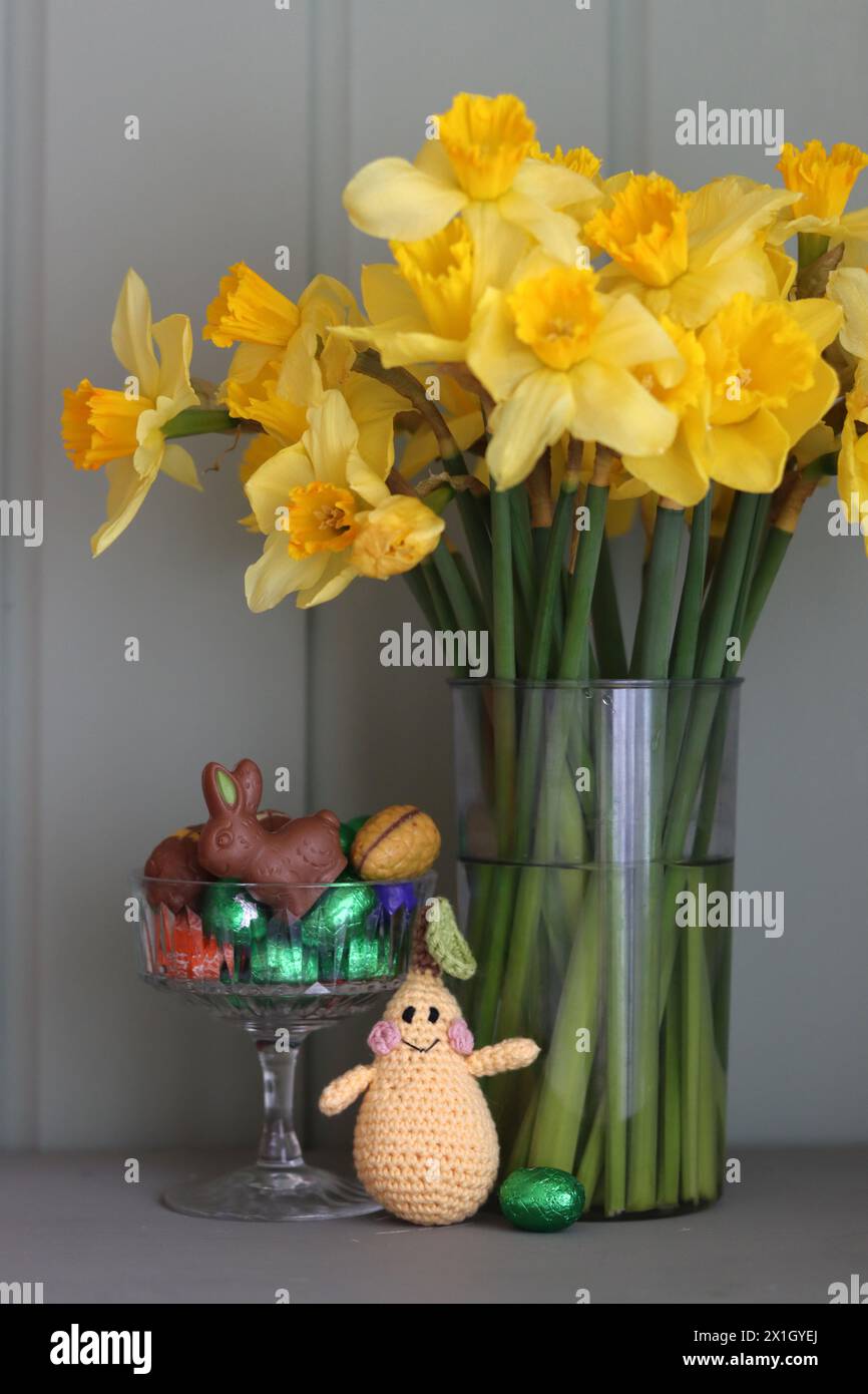 Bouquet de jonquilles dorées dans un vase en verre sur fond de bois vert avec espace pour le texte. Banque D'Images