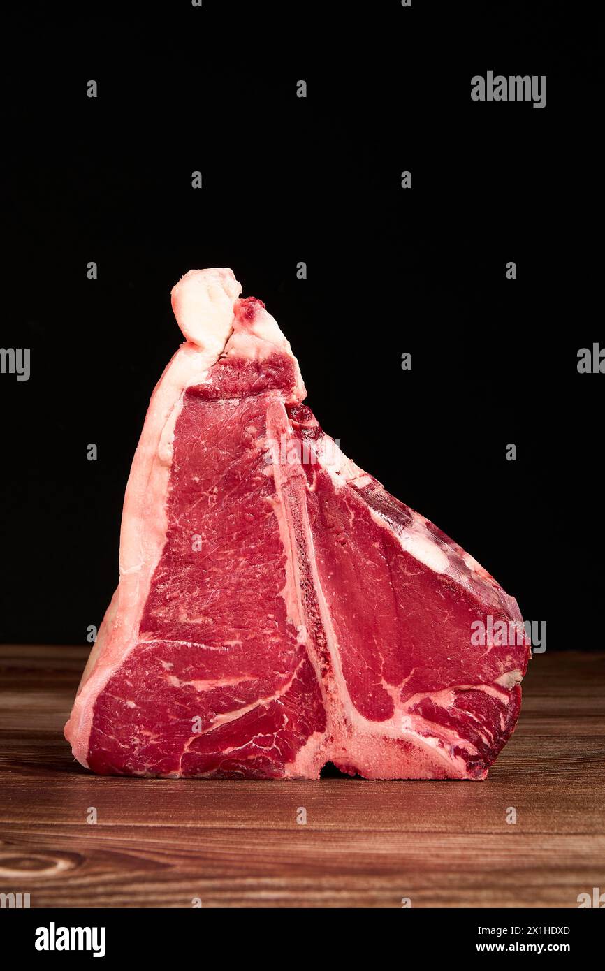 Morceaux de viande prime sur une table en bois sur un fond noir foncé Banque D'Images