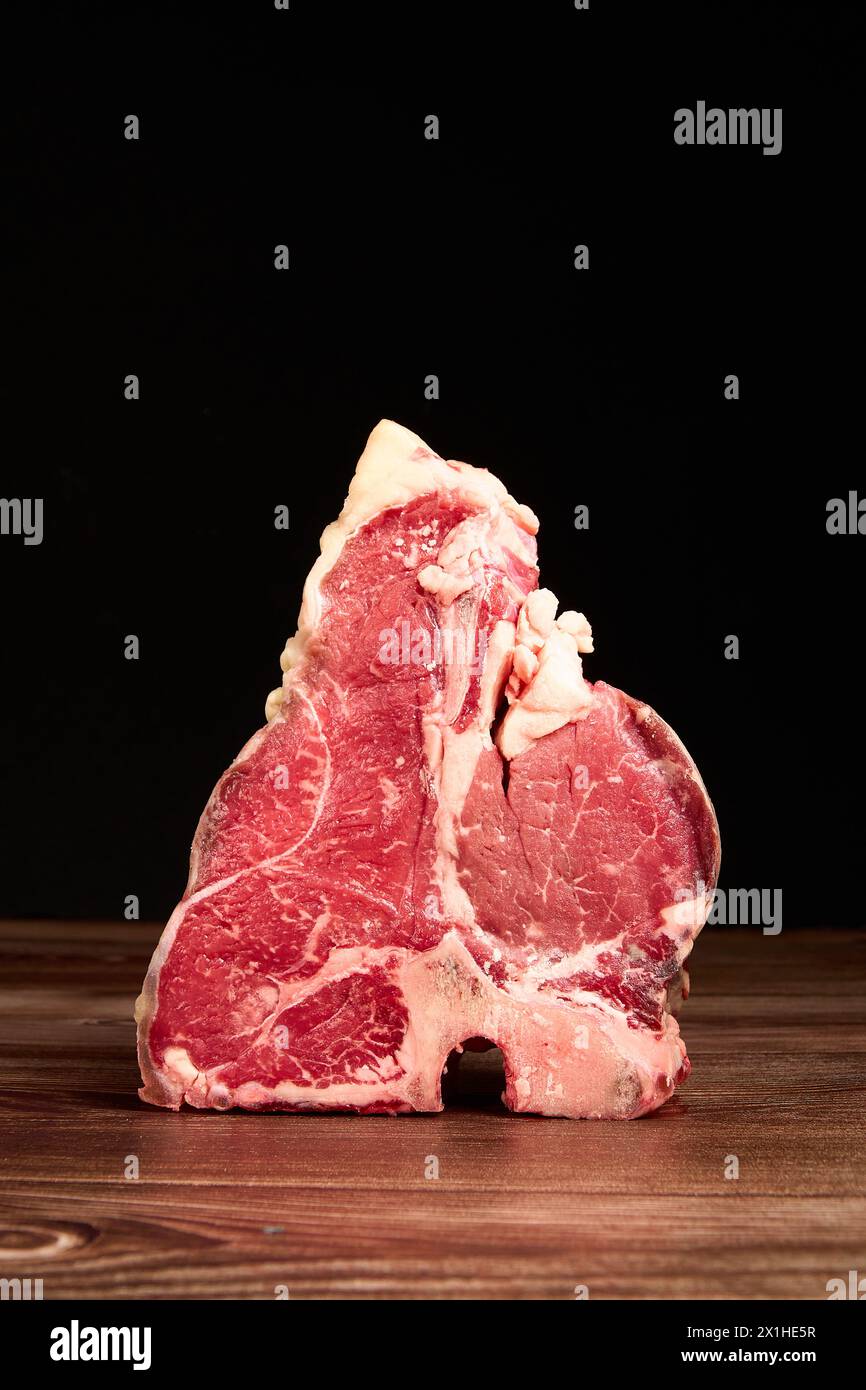 Morceaux de viande prime sur une table en bois sur un fond noir foncé Banque D'Images