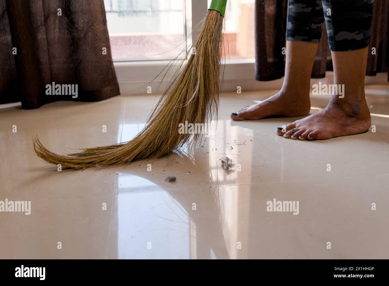 Une femme concentrée balaye le sol avec un balai, gardant son espace de vie propre et organisé. Banque D'Images