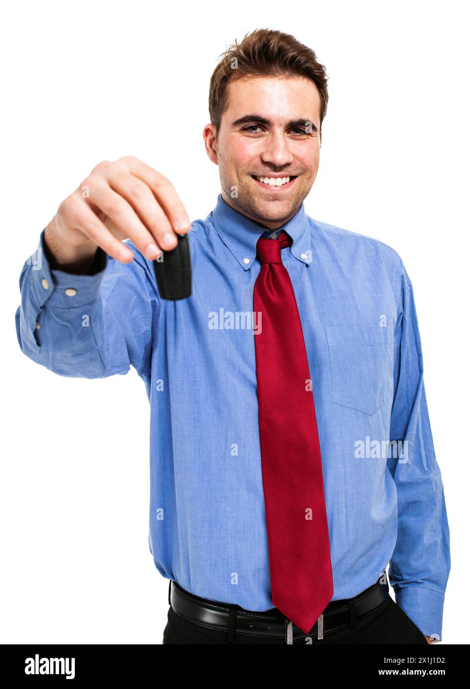 Souriant jeune homme d'affaires adulte dans une tenue formelle offrant une clé de voiture tout en se tenant sur un fond blanc Banque D'Images