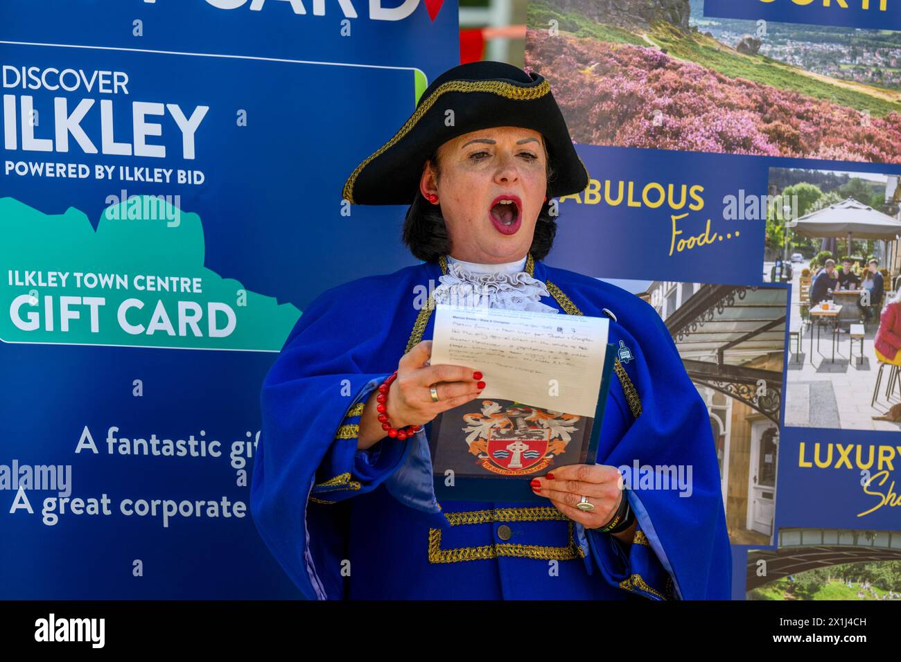 Les vêtements bleus de la femme crier de la ville) proclamant oyez, faisant une proclamation publique forte et annonce - Ilkley, West Yorkshire, Angleterre, Royaume-Uni. Banque D'Images
