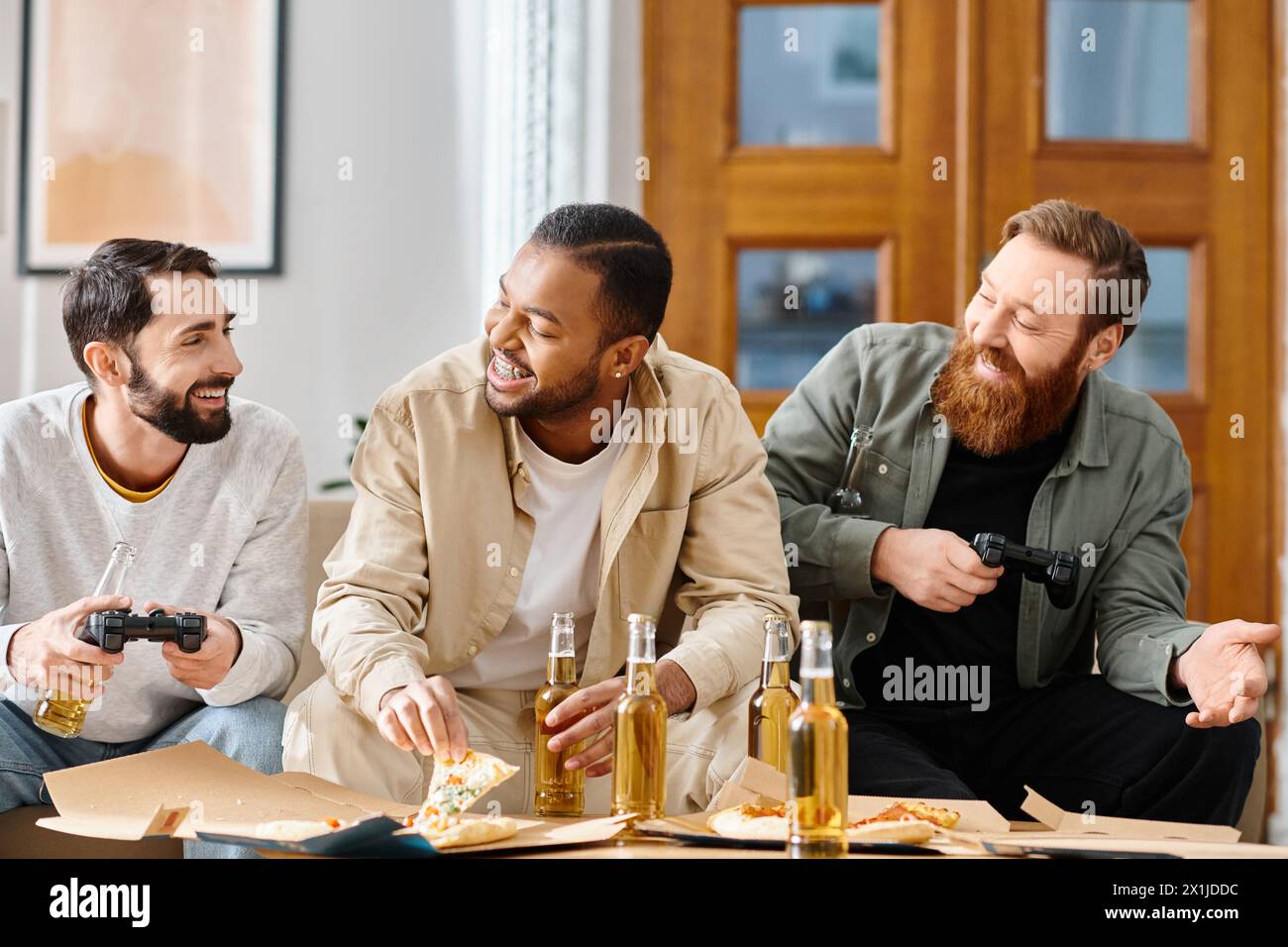 Trois hommes joyeux et interraciaux dans une tenue décontractée profitant d'une session de jeu autour d'une table à la maison. Banque D'Images