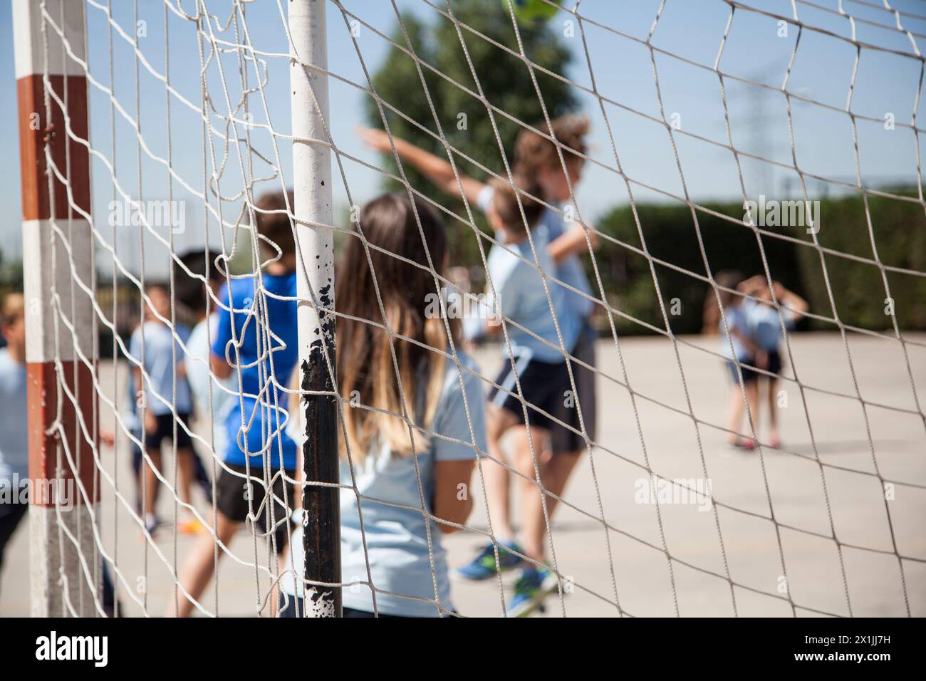 enfants jouant au football après le but dans la cour de récréation d'une école primaire Banque D'Images