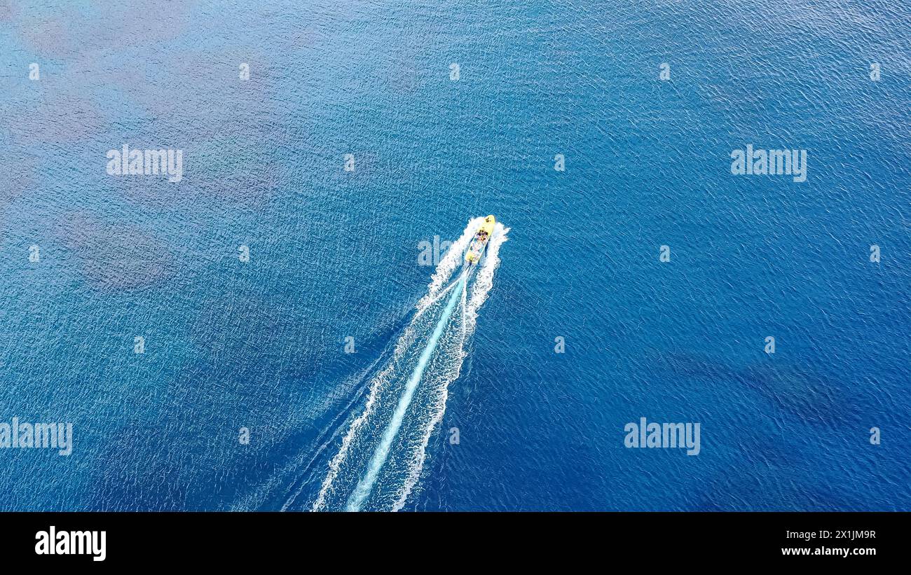 Le bateau navigue en pleine mer, laissant un sillage blanc. Drone vu à vol d'oiseau. Journée ensoleillée, vagues de mer légères Banque D'Images