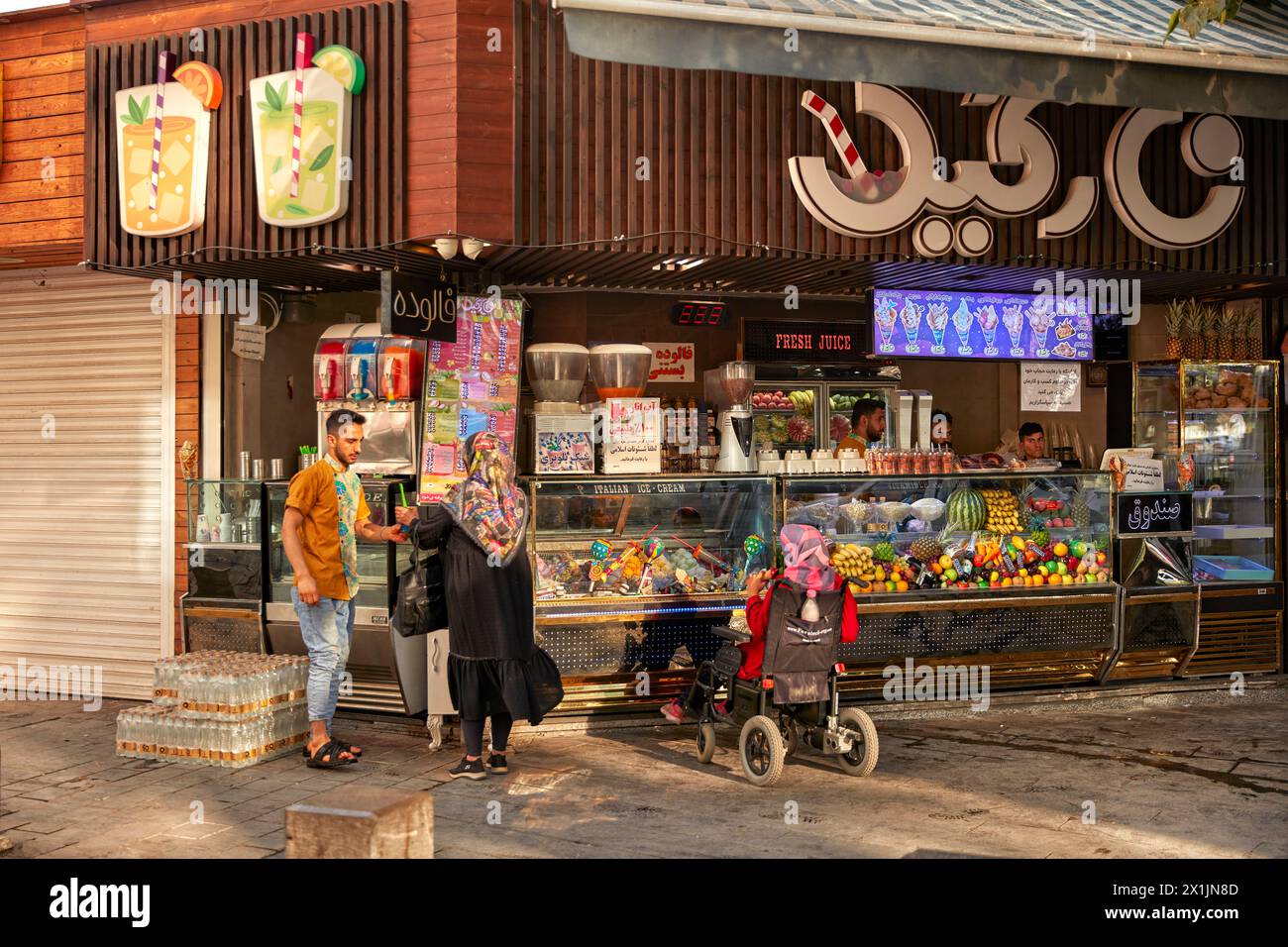 Des iraniennes achètent du jus de fruits fraîchement pressé et de la crème glacée à un vendeur de rue dans la Nouvelle Julfa, quartier arménien d'Ispahan, en Iran. Banque D'Images