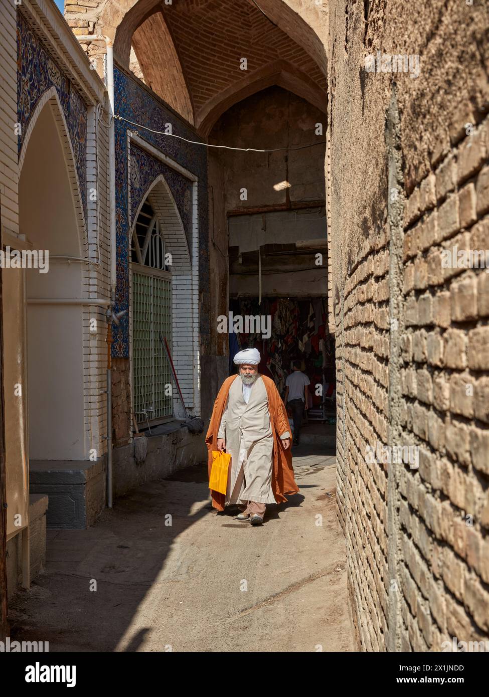 Un iranien vêtu de vêtements religieux musulmans traditionnels marche dans une ruelle étroite du Grand Bazar d'Ispahan, en Iran. Banque D'Images