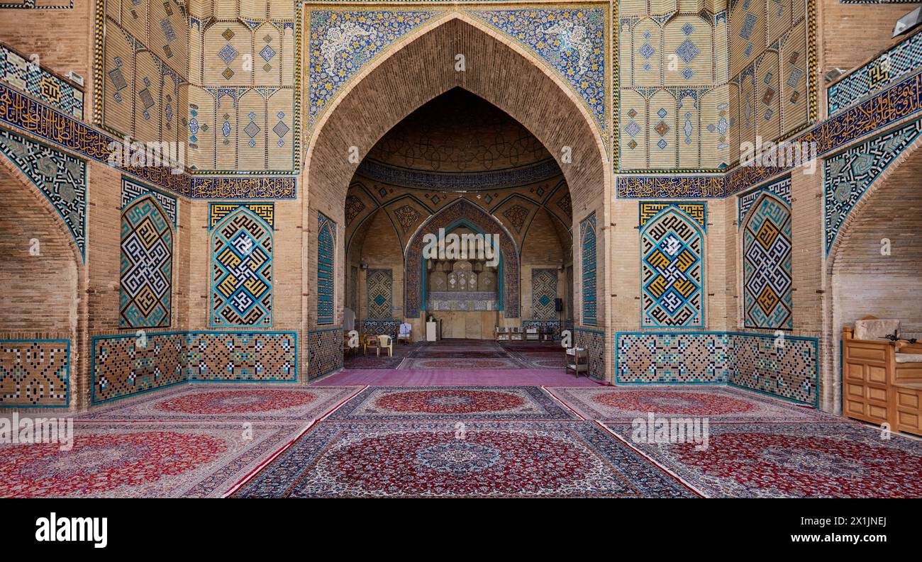 Vue panoramique intérieure de la mosquée Hakim avec mosaïques carrelées ornées sur ses murs de briques et moquette. Ispahan, Iran. Banque D'Images