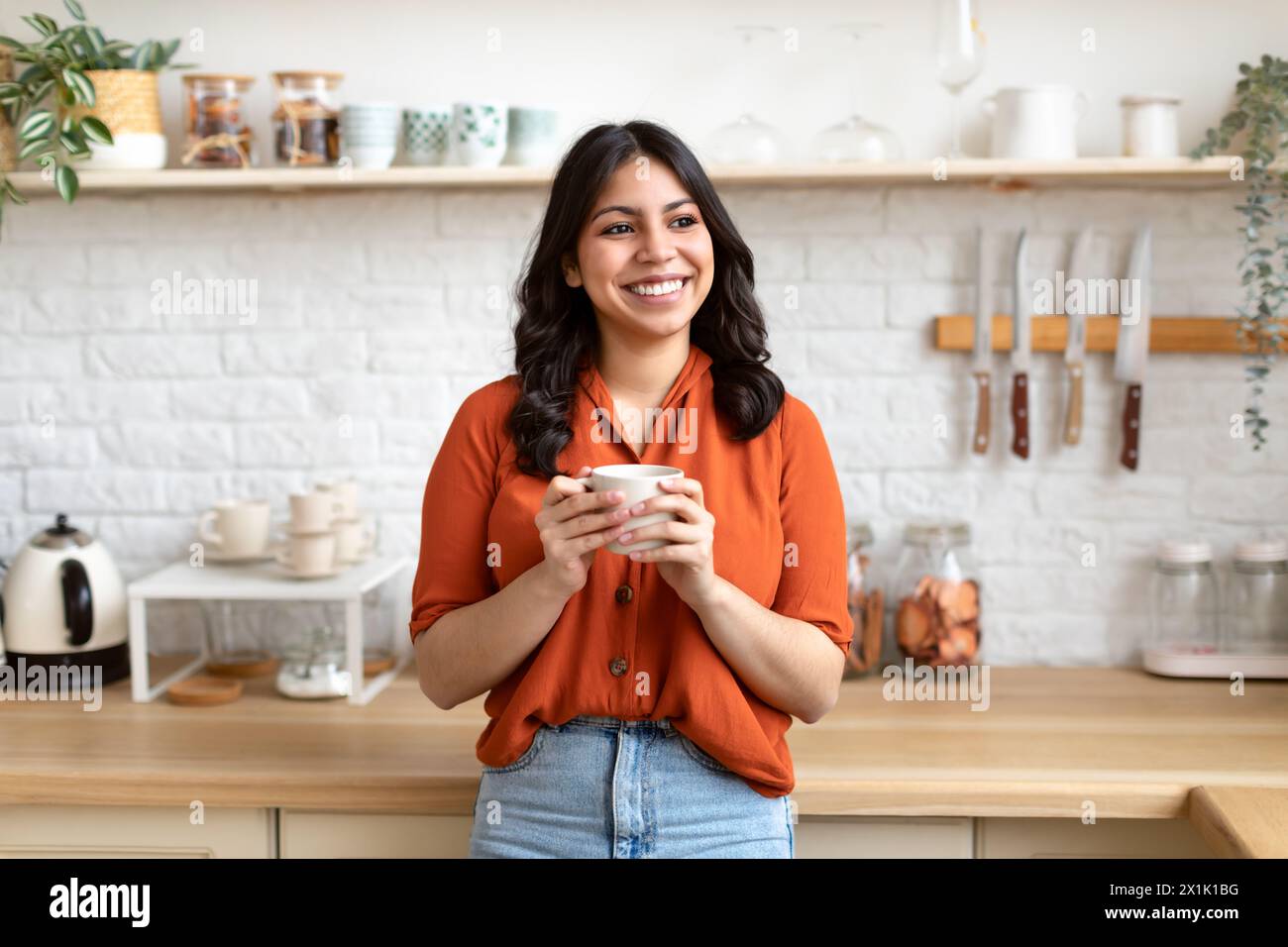 Femme joyeuse du moyen-Orient debout dans la cuisine moderne Banque D'Images