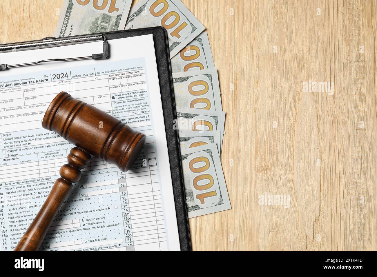 Presse-papiers avec formulaire de déclaration d'impôt, marteau et billets de banque en dollars sur table en bois, pose à plat. Espace pour le texte Banque D'Images