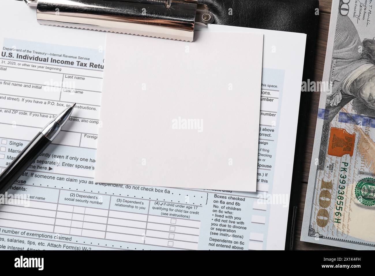 Formulaire de déclaration de revenus, billet papier, billets de banque en dollars et stylo sur la table, vue de dessus Banque D'Images