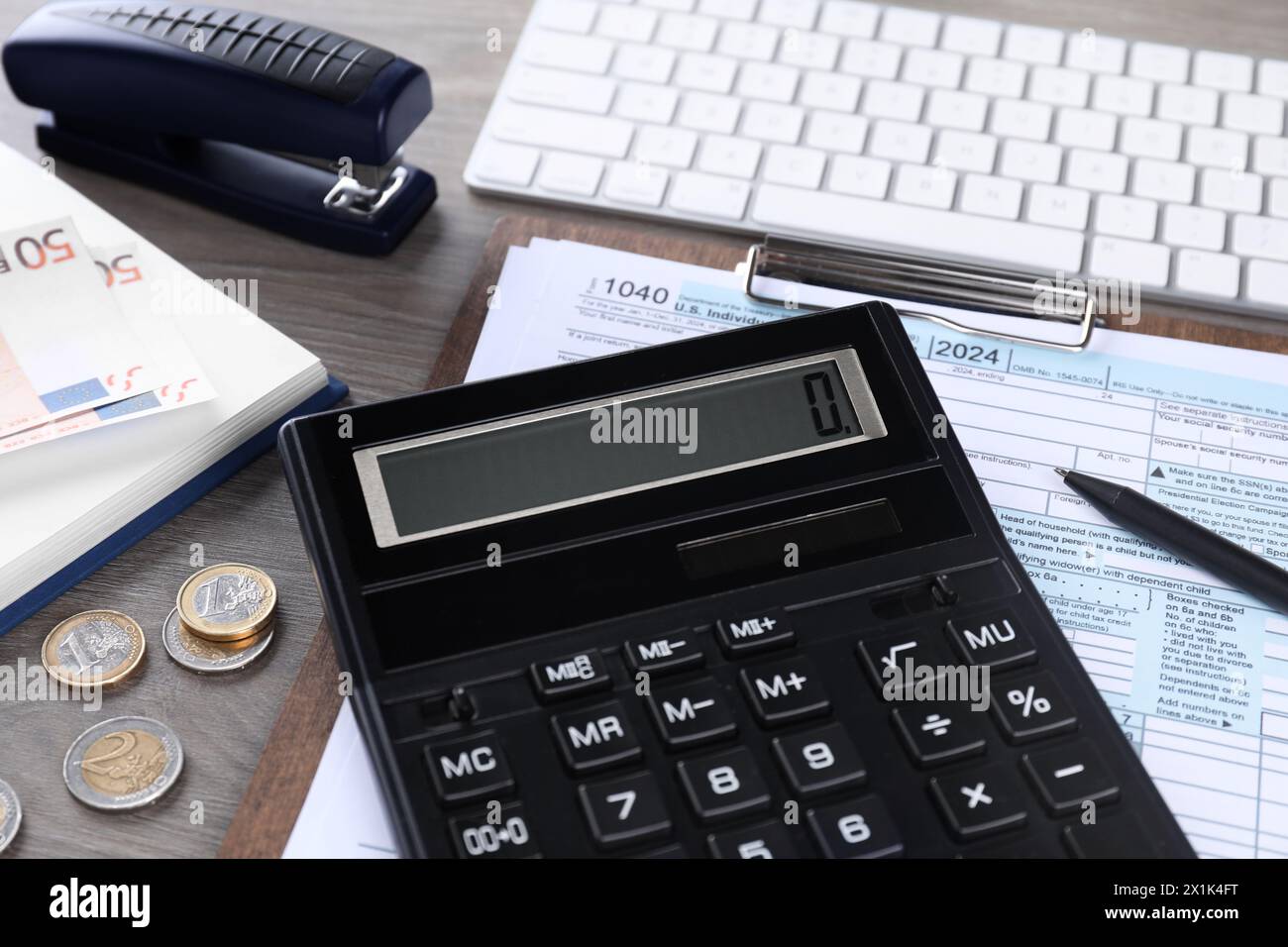 Comptabilité fiscale. Calculatrice, document, pièces de monnaie, clavier et papeterie sur table en bois, gros plan Banque D'Images