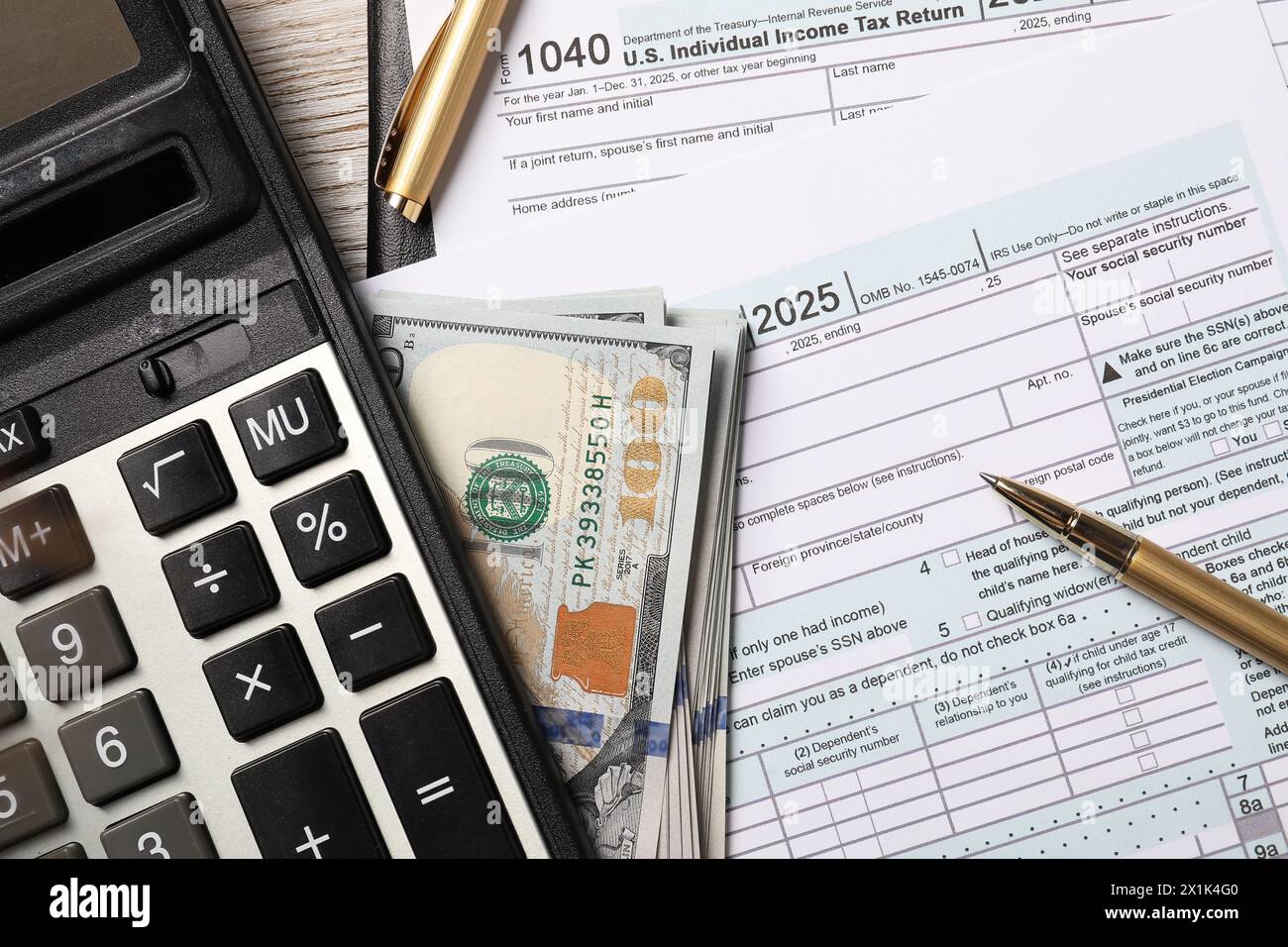 Formulaires de déclaration d'impôt, billets de banque en dollars, calculatrice et stylo sur la table, pose à plat Banque D'Images
