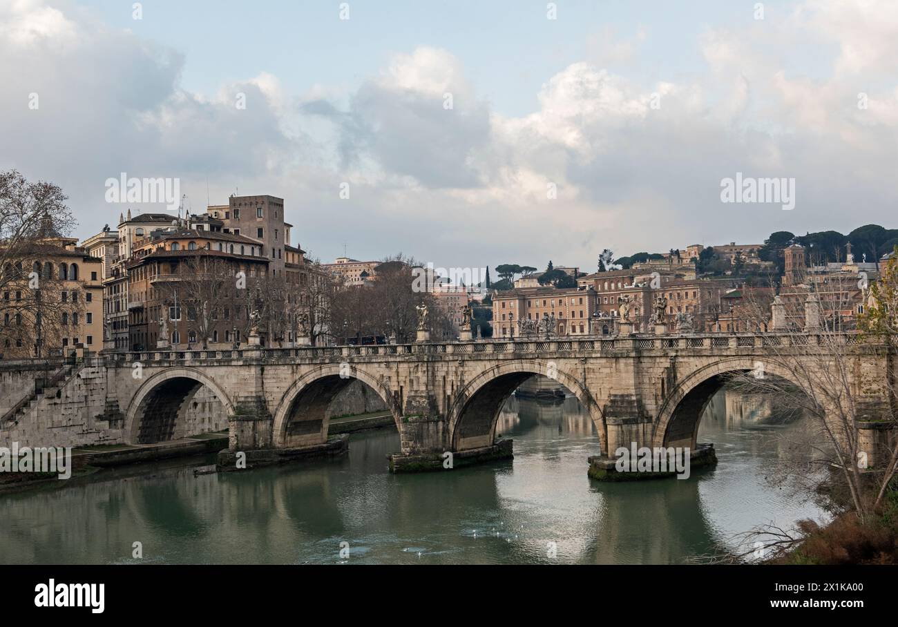 Vieux pont routier voûté en pierre sur la grande rivière Tibre dans le centre-ville européen de Rome avec ciel nuageux couvert Banque D'Images