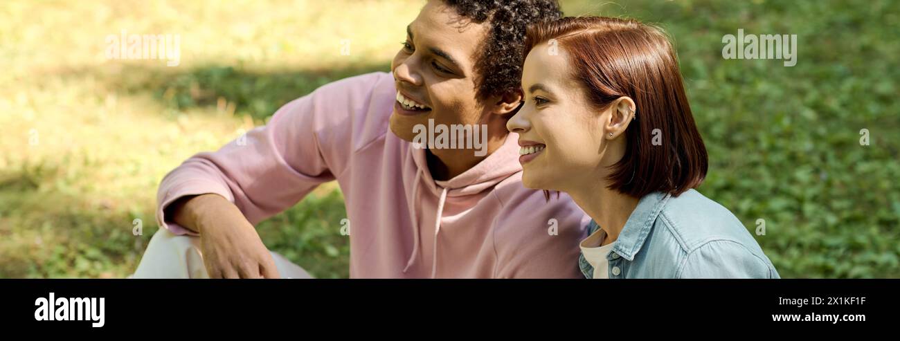 Un couple aimant dans une tenue vibrante est assis à proximité l'un de l'autre dans un parc, rayonnant de bonheur et de connexion. Banque D'Images