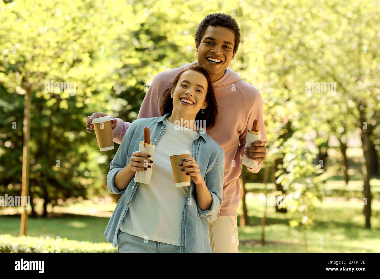 Couple diversifié dans une tenue vibrante dégustant un café ensemble dans le parc par une journée lumineuse. Banque D'Images