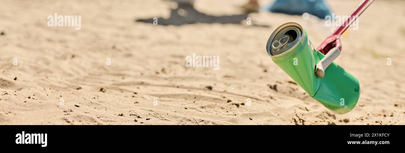 Une canette de soda pend d'une corde sur la plage, projetant des ombres ludiques dans le sable. Banque D'Images