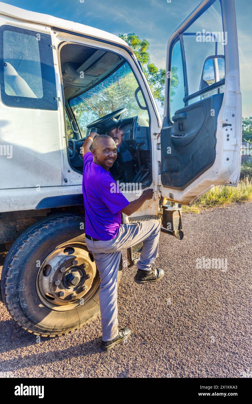 conducteur africain entrant dans la cabine du camion, vue de profil, transport dans la ville Banque D'Images