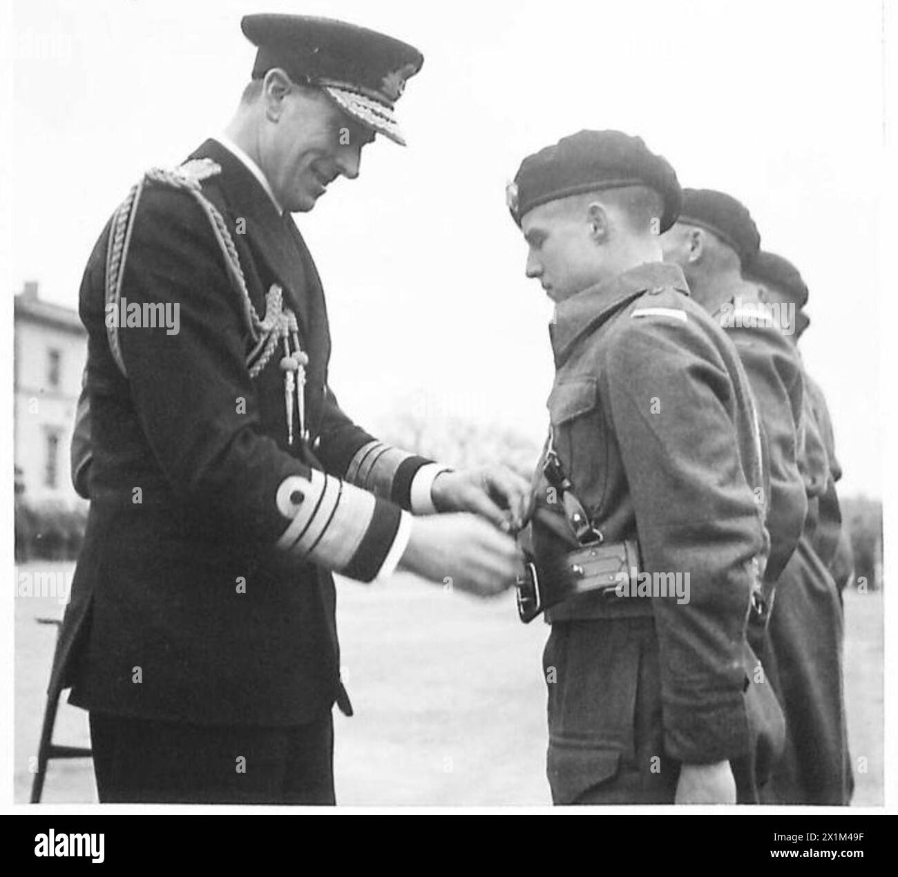 LE VICE-AMIRAL LORD LOUID MOUNTBATTEN PREND LE SALUT AU DÉFILÉ DE LA R.A.C. - Sam Browne Belts sont présentés à des cadets exceptionnels. Le vice-amiral Lord Louis Mountbatten est vu ajuster la ceinture d'un cadet de l'armée britannique Banque D'Images