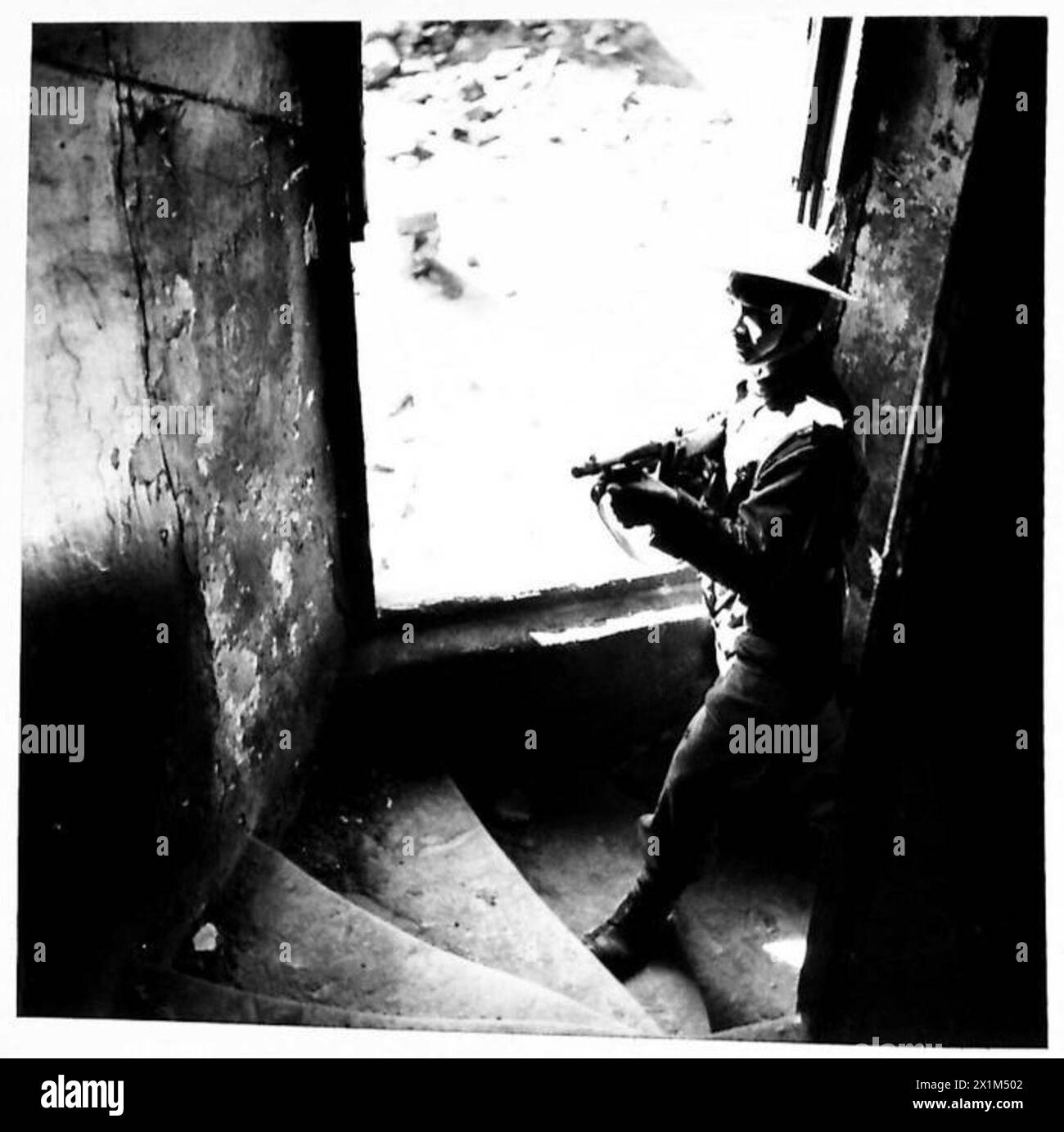 Les troupes manifestent en entrant dans une maison et en montant un escalier avec un pistolet Tommy préparé lors de combats de rue réalistes, British Army. Banque D'Images