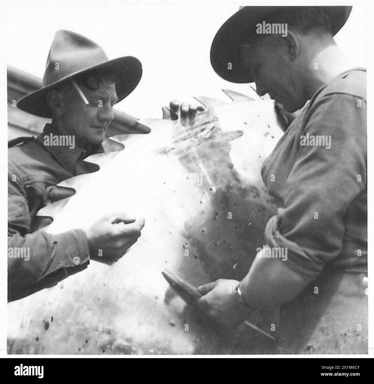 Les bushmen néo-zélandais employés par l'armée britannique testent une grande scie circulaire pour vérifier la tension dans une scierie sous supervision. Banque D'Images
