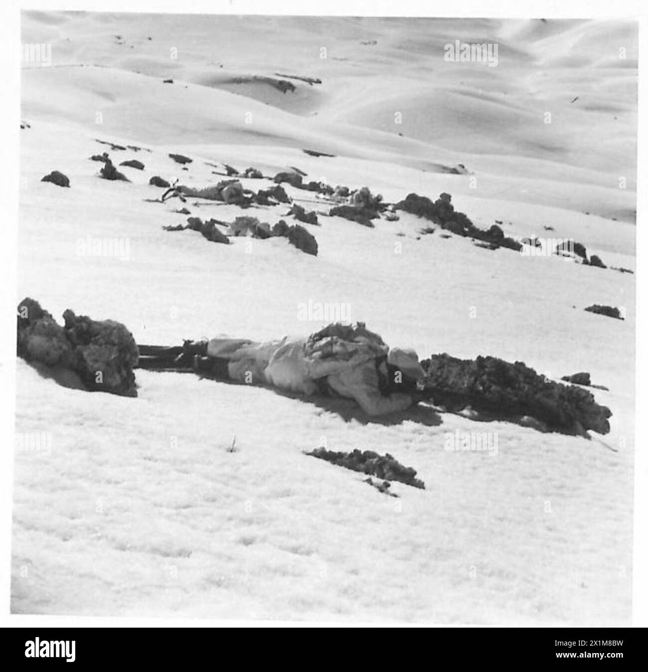 Les troupes de ski se mettent à couvert derrière des rochers sur un terrain enneigé pendant les exercices d'entraînement de l'armée britannique. Banque D'Images