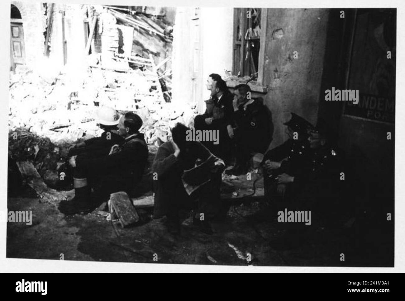 ACTEURS DE CINÉMA AFS : LE TOURNAGE DE 'L'HISTOIRE INÉDITE' AUX STUDIOS DE CINÉMA DE DENHAM, DENHAM, BUCKINGHAMSHIRE, ANGLETERRE, ROYAUME-UNI, 1941 - les hommes de la brigade de pompiers d'Uxbridge s'assoient parmi les décombres et les débris sur le plateau et regardent l'action se dérouler autour d'eux pendant le tournage du film de Two Cities film Company 'Unpublished Story' aux studios de cinéma de Denham dans le Buckinghamshire. Le film est réalisé par Harold French et met en vedette Richard Greene et Valerie Hobson. Il se déroule pendant le Blitz sur les quais de Londres en 1940, Banque D'Images