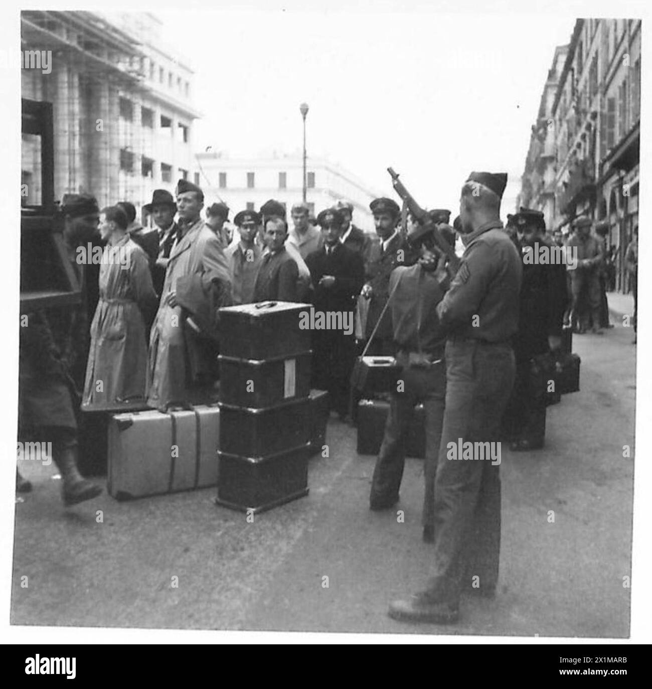 Un soldat américain armé d'un fusil Tommy garde les prisonniers italiens devant l'hôtel Angleterre à Alger, occupé par les Alger, le 14 novembre 1942, avant qu'ils ne soient emmenés sur les quais. Le personnel de l'armée italienne et de l'armée américaine est présent. Banque D'Images