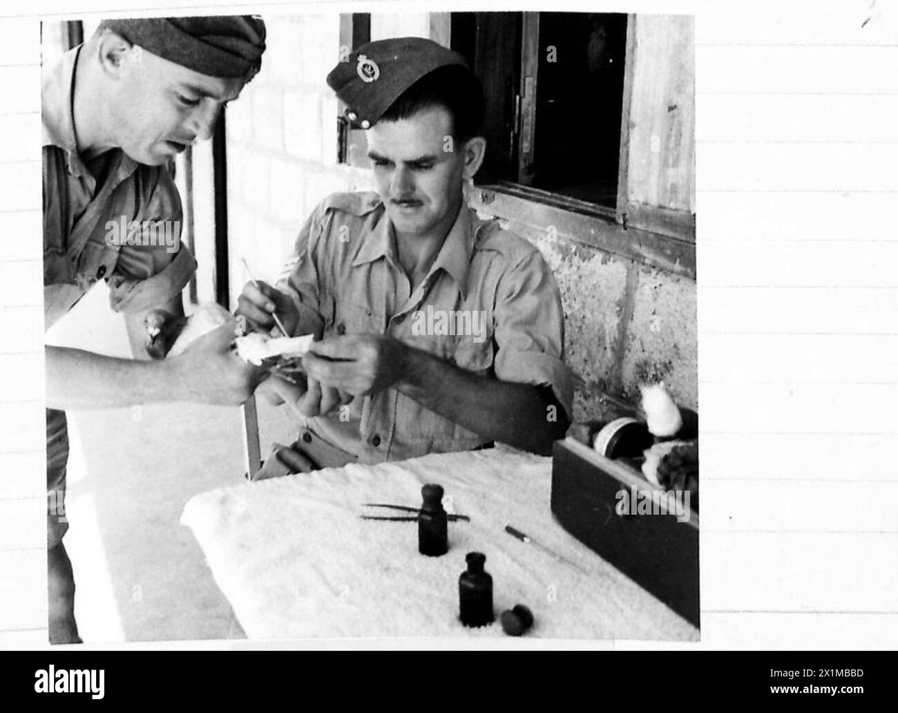 Le sergent Sidney Patey s'occupe d'un pigeon porteur blessé détenu par le caporal J. Bent au Middle East Pigeon Service Breeding Centre le 9 juillet 1943. Les pigeons ont été utilisés par l'armée britannique pour transporter des messages pendant la seconde Guerre mondiale. Seules des races spécifiques étaient appropriées, et le personnel formé a maintenu sa santé et remplacé les victimes si nécessaire. Banque D'Images