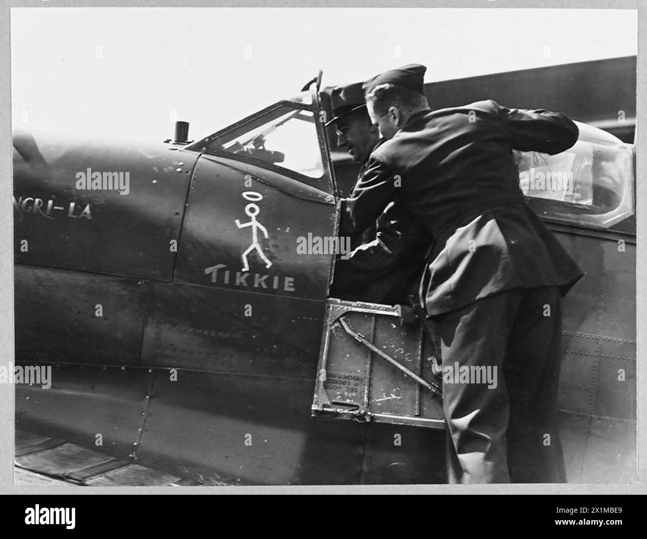 Le député australien B.H. Corser est assis dans un cockpit de Spitfire dans une station de chasse de la RAF en Angleterre pendant qu'un officier du génie explique l'avion. Banque D'Images